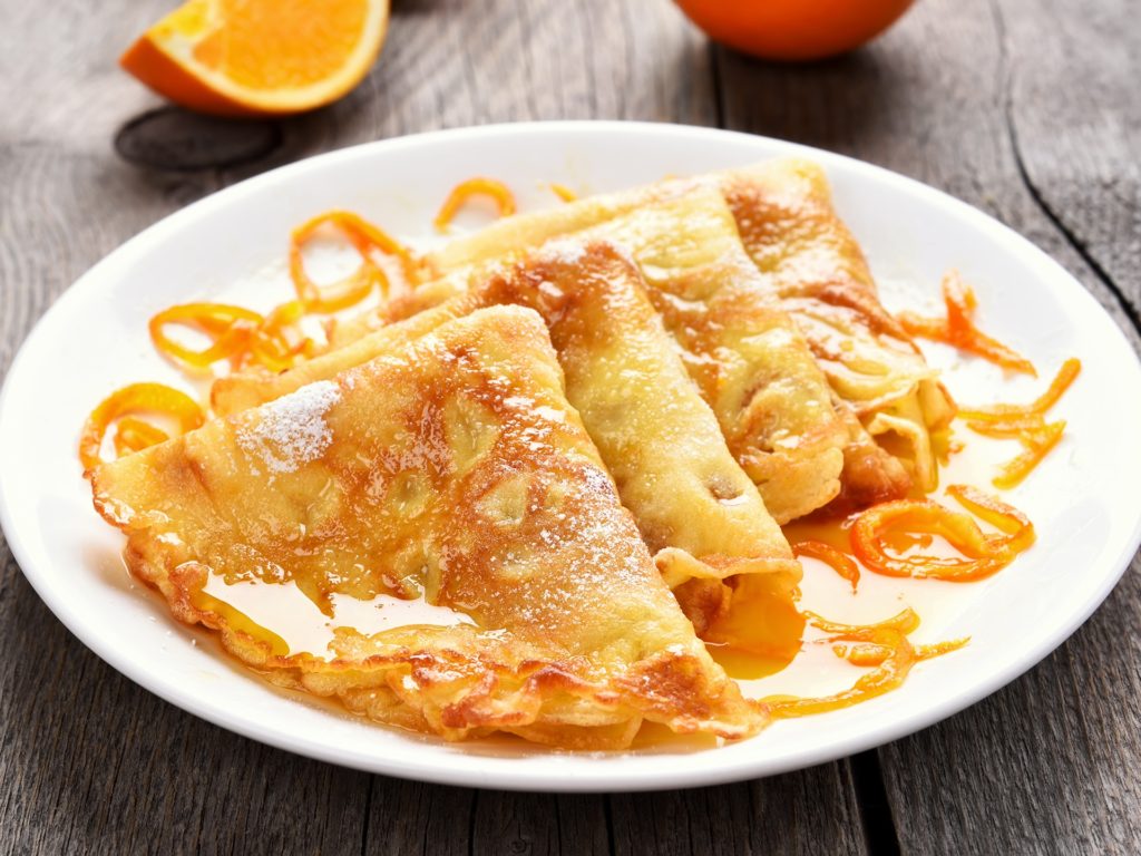 Crepes Suzette on white plate over wooden background