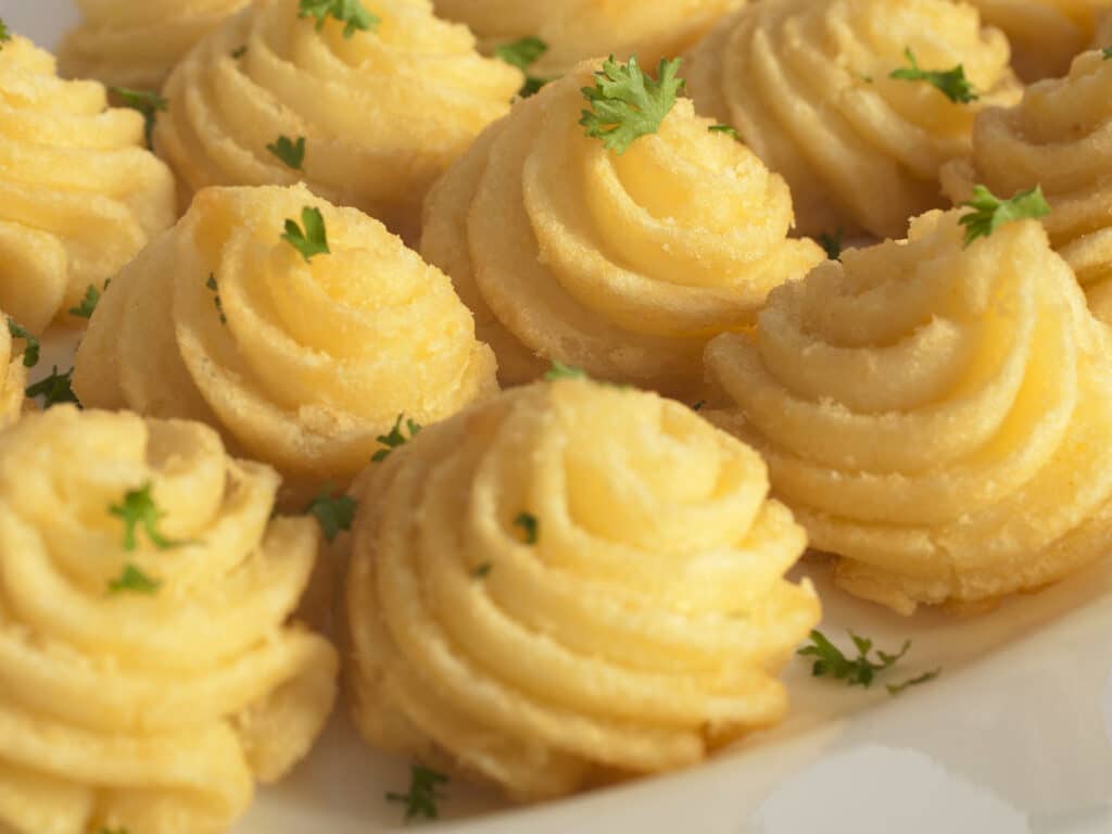 Duchess potatoes, mashed potato mixed with egg, piped into swirls and baked in the oven.
