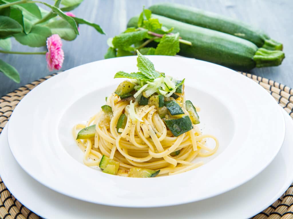 plate of spaghetti with zucchini and mint leaves