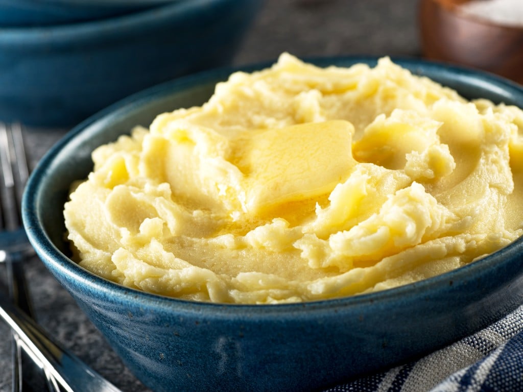 A bowl of delicious mashed potatoes with melted butter.