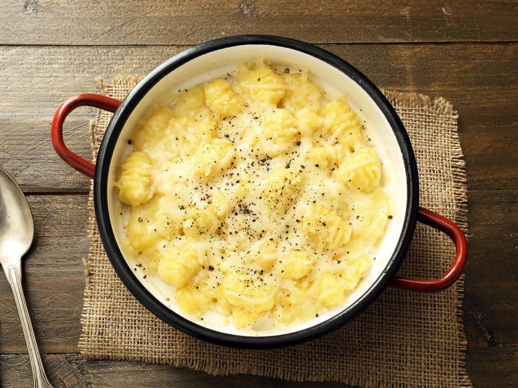 italian pasta gnocchi with cheese in metal pan on rustic wooden table