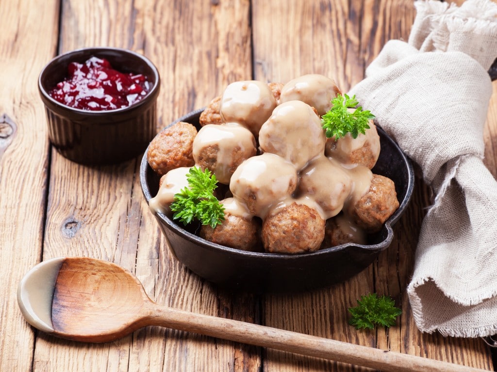 Traditional meatballs with sauce in a cast iron skillet on wooden background