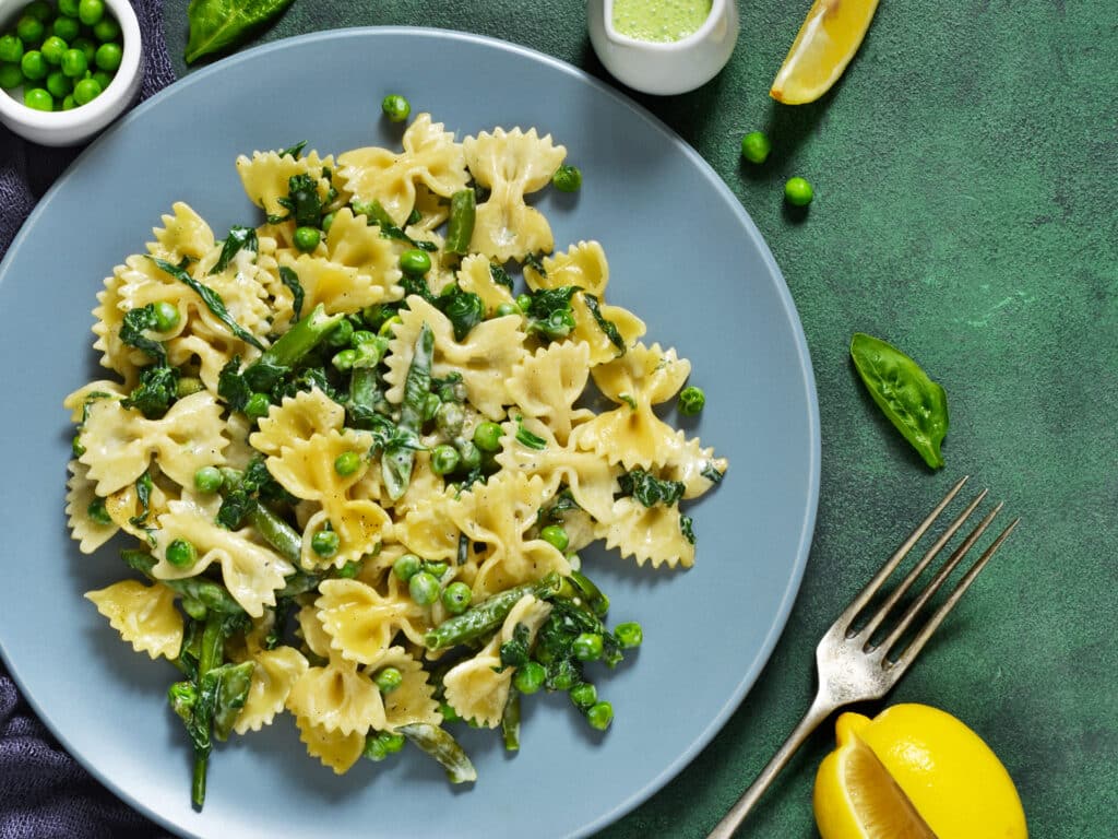 Farfalle with asparagus sauce, green peas and spinach green background. Homemade dinner.