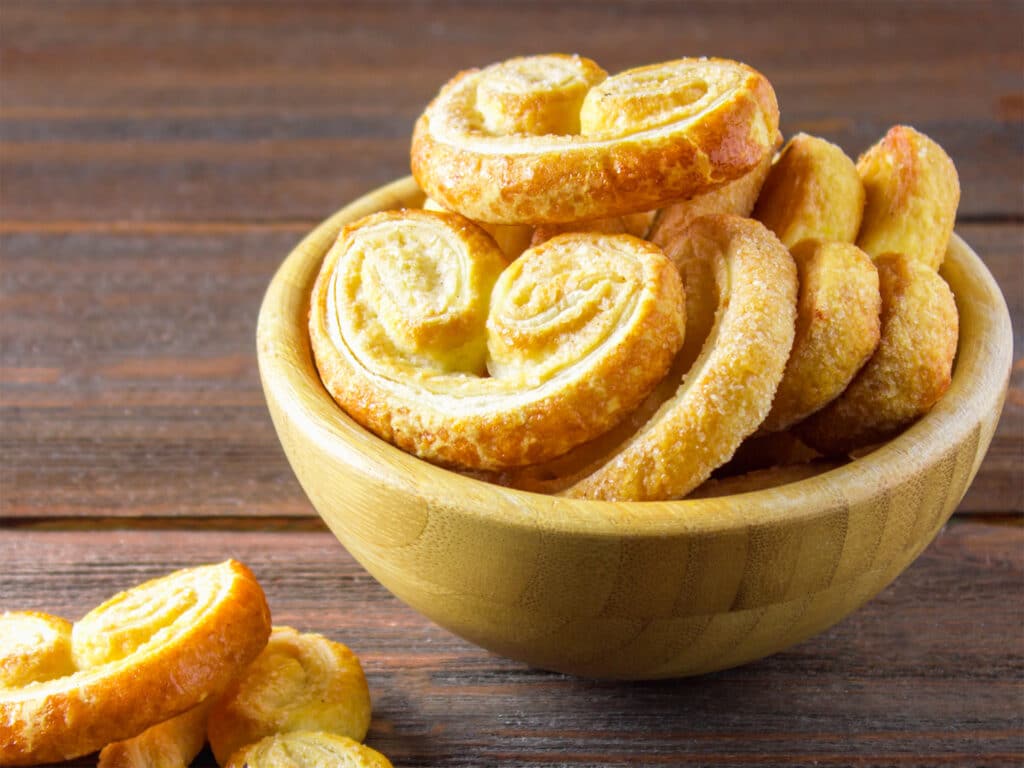 Sweet pretzels made of puff pastry in a bowl on a wooden table