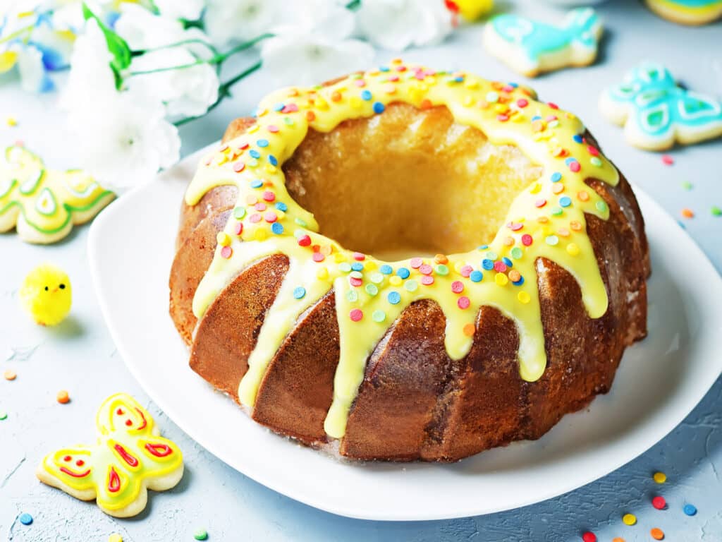 Easter Bundt cake with colorful topping and Easter Cookies on a stone background. tinting. selective focus