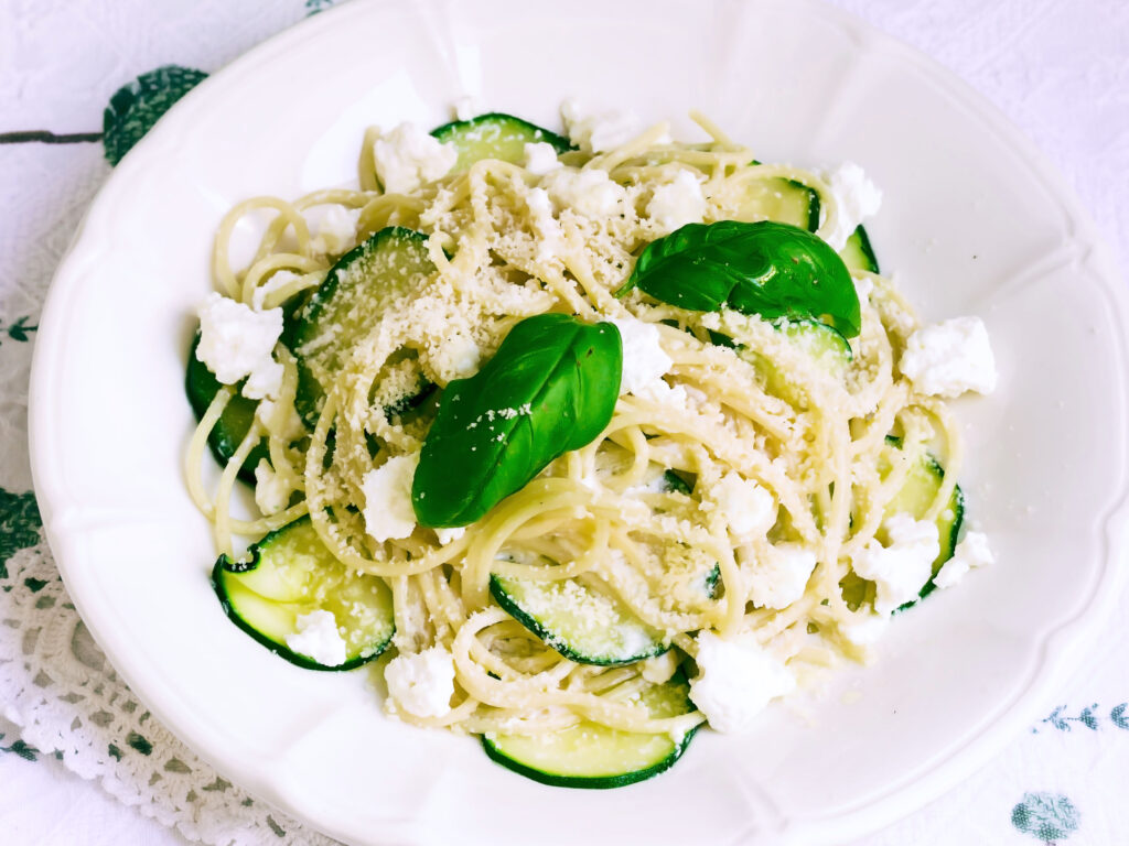 Vegetarian Pasta Spaghetti with zucchini and ricotta cheese served on a white plate. Italian Food, recipes. Mediterranean Kitchen. Top view.