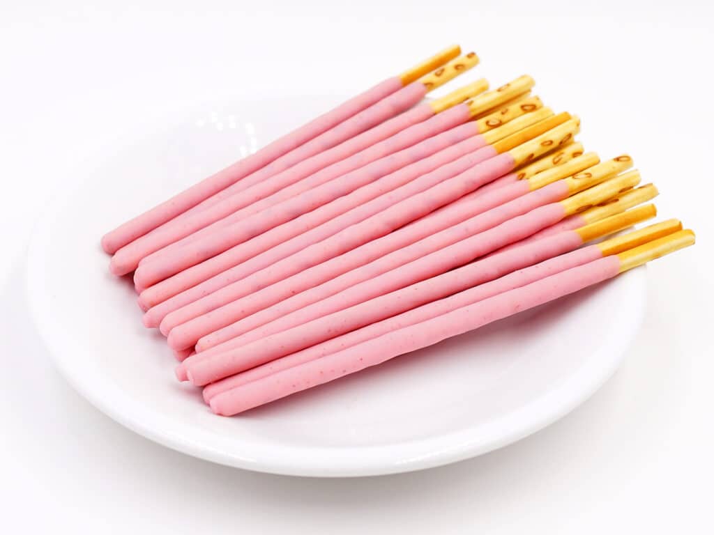 Biscuit sticks coated with strawberry flavour confectionery